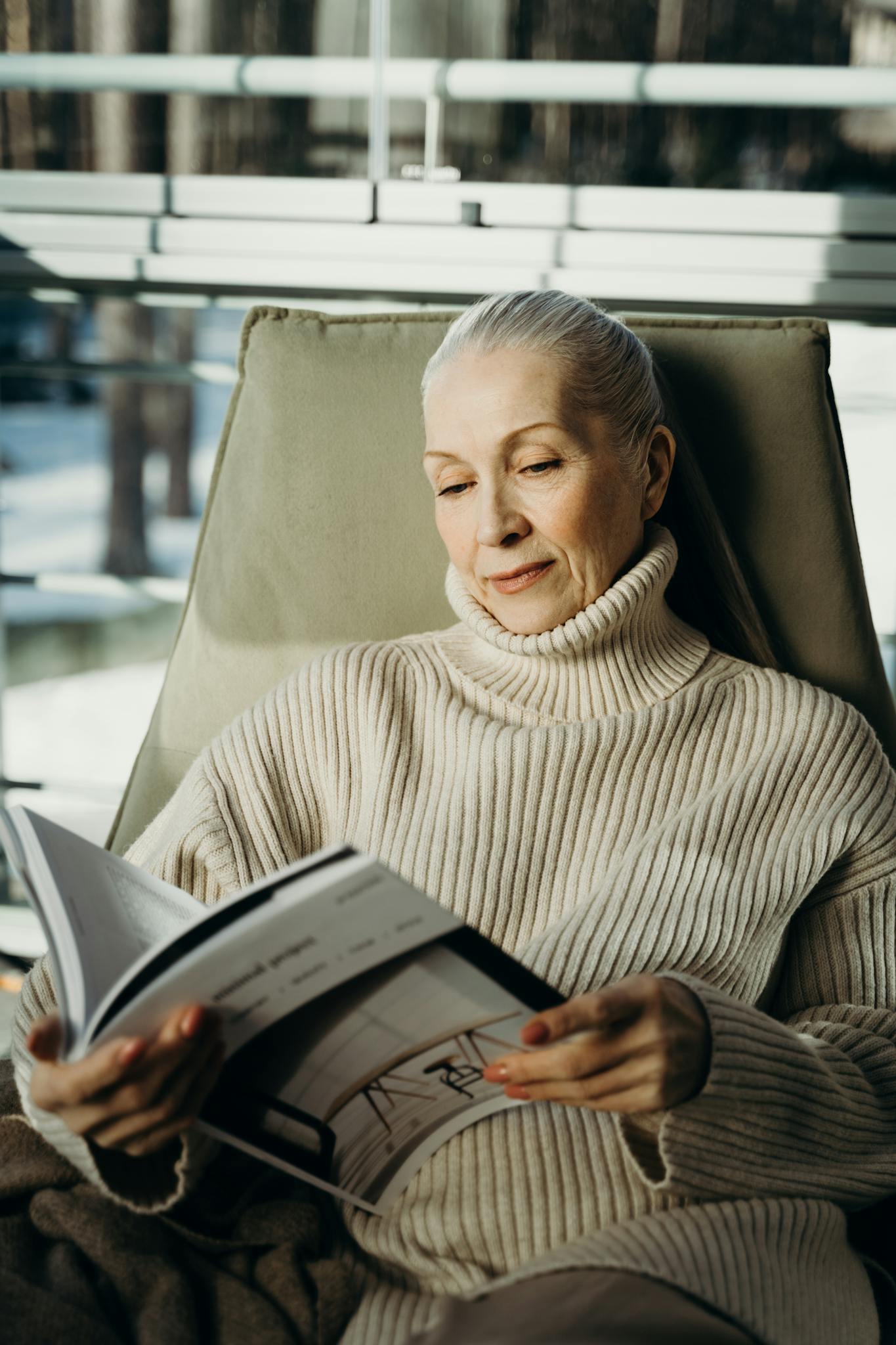 Senior woman enjoying a peaceful moment reading a magazine indoors.
